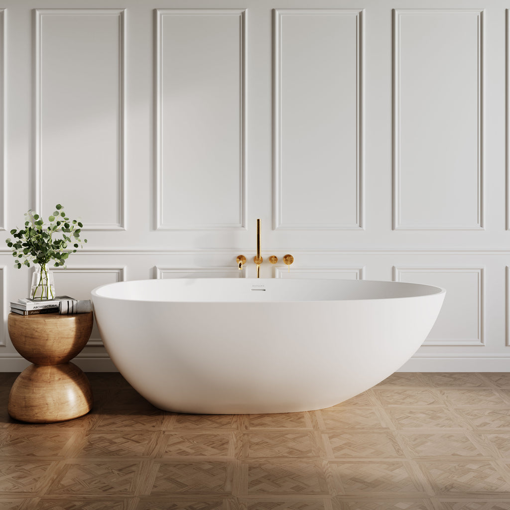 Egg shaped stone resin bath in matte white colour, on parque wood floor, against panelled white wall