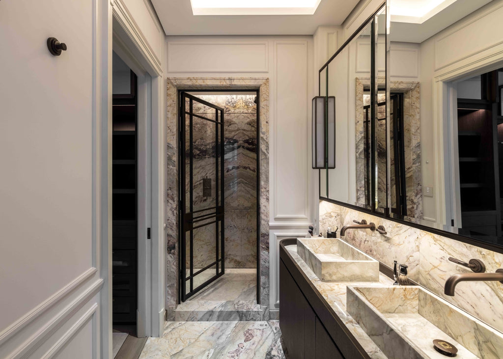 Luxury interior bathroom with white & cream carerra marble finish and brushed bronze taps